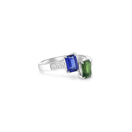 Two stunning gemstones - tsavorite and tanzanite - set in an elegant Toe Et Moi ring. Close-up of the exquisite green tsavorite gemstone in the Toe Et Moi ring. Mesmerizing violet-blue tanzanite gemstone showcased in the luxurious ring design. A side view of the Tsavorite & Tanzanite Ring highlighting the intricate craftsmanship. The Toe Et Moi ring featuring a harmonious blend of tsavorite and tanzanite gemstones.
